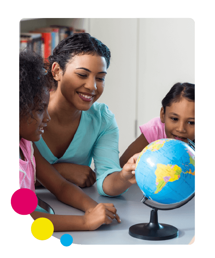 A happy teacher sits at a table with her students and shows them a globe of the world