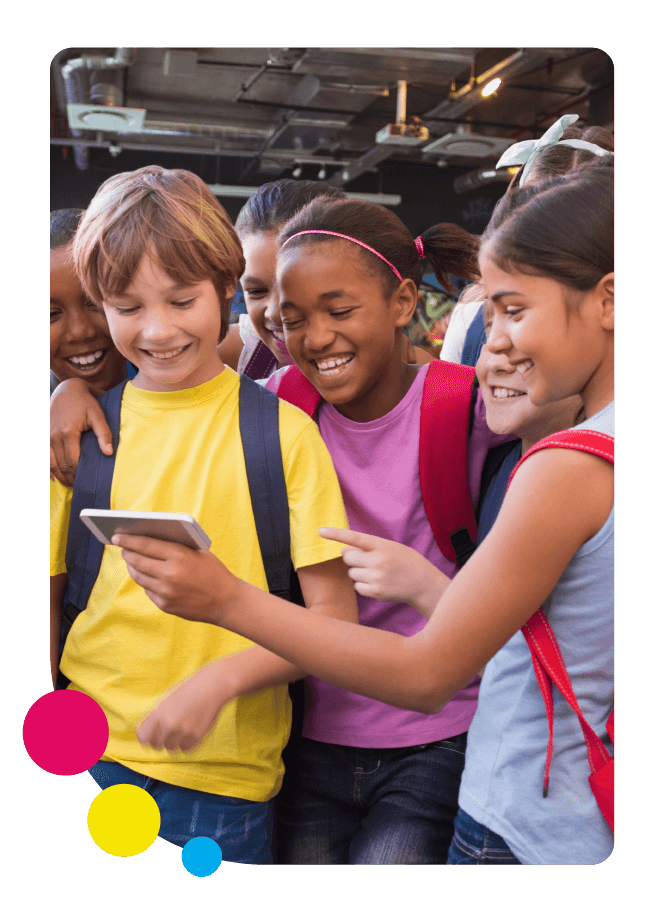 Students stand together in school looking at a phone and laughing